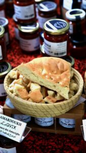 A woven grass basket contains "tabouna" bread that will be used for tasting harissa, contained in jars laid out around the basket