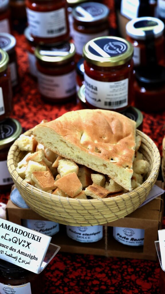 A woven grass basket contains "tabouna" bread that will be used for tasting harissa, contained in jars laid out around the basket